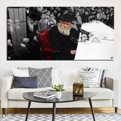 320 – תמונה מלבנית של הרבי מליובאוויטש מחייך ויושב על כיסא אדום בהתוועדות